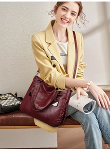 Detail of burgundy leather tote bag with silver zippers and studs on a yellow blazer outfit