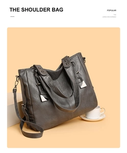 Detail of soft leather tote bag showing rivet-reinforced handles and silver hardware décor