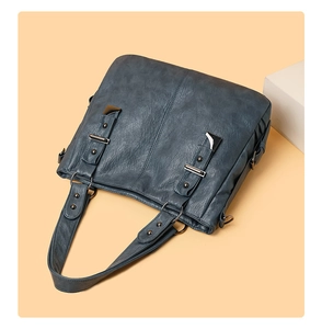 Detail of vintage dark blue tote bag showing matte leather texture and metal rivets