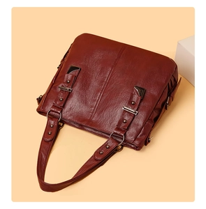 Detail of burgundy leather tote bag featuring vertical straps and silver hardware accents