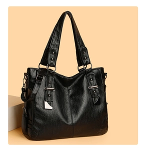 Detail of black pebbled leather tote bag with silver rivets and metal hardware accents