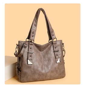 Detail of soft dark brown pebble leather texture and side buckles on tote bag