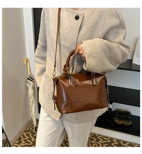Détails d'un sac Boston marron foncé en cuir brillant avec des ferrures dorées