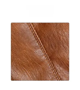 Detailed close-up of brown leather texture and reinforced double stitching on the tote bag