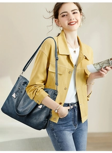 Detail of dark blue soft leather tote bag with shoulder strap worn by a model