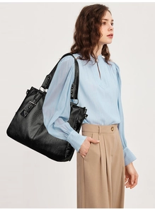 Close-up of black tote bag with lychee texture and silver hardware details on a model