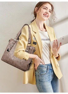 Detail of dark brown leather tote bag showing smooth matte texture and metal buckle