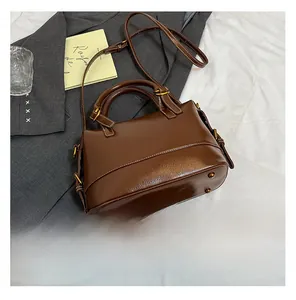 Détail d'un sac en cuir ciré marron foncé avec pieds dorés et texture raffinée