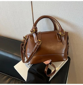 Détail de la texture en cuir grainé marron foncé et des ferrures dorées de ce sac à main