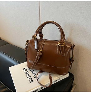 Détail du sac à main marron avec surpiqûres blanches contrastées et ferrures dorées