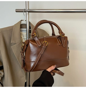Détails de la texture en cuir PU marron poli avec des boucles en métal doré sur le sac