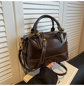 Détail d'un sac Boston marron foncé avec coutures blanches et finitions dorées