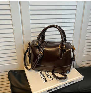 Détail d'un sac Boston vintage en cuir marron avec surpiqûres blanches et ferrures dorées