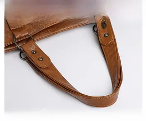 Detail of caramel brown faux leather handbag with reinforced straps and metal ring accents