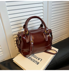Vue détaillée d'un sac à main vintage rouge foncé avec surpiqûres blanches sur un support