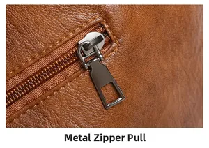 Detailed close-up of hardware zipper pull on brown lychee grain leather handbag