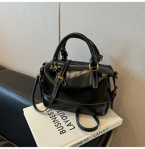 Détail du sac en cuir brillant noir avec coutures blanches et boucles dorées