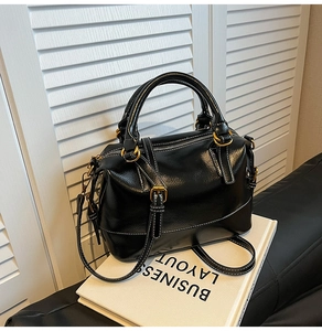 Détail du sac Boston noir avec surpiqûres blanches et accessoires en métal doré