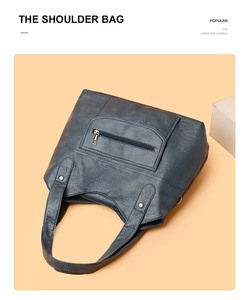 Close-up of navy blue PU leather tote bag showing front zipper detail and soft texture