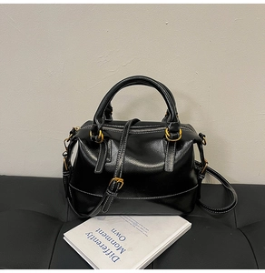 Détail d'un sac Boston en cuir noir brillant avec surpiqûres blanches et dorure élégante