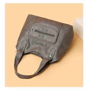 Detail of dark brown faux leather tote bag with front zipper pocket and metal rivets