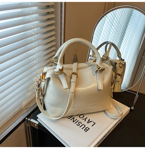 Détail du sac Boston blanc crème montrant la texture du cuir et la boucle dorée