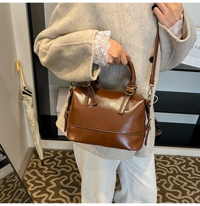 Détail d'un sac à main en cuir marron motif litchi avec anneaux dorés et bandoulière assortie