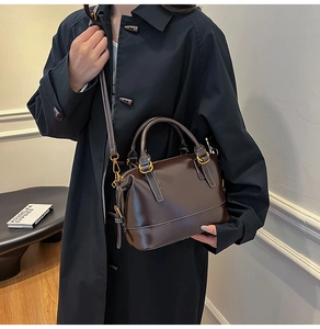 Détail du sac à main marron foncé brillant avec ferrures dorées et doubles poignées