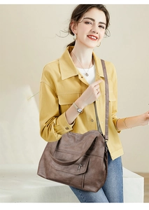 Detail of dark brown faux leather tote bag with exterior zip pocket and pebble grain texture