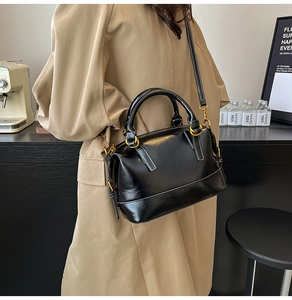 Détail d'un sac à main noir brillant avec surpiqûres contrastées blanches et métal doré