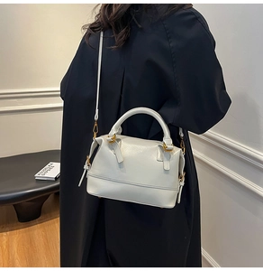 Détail d'un sac à main beige en cuir avec boucles dorées et bandoulière sur un mannequin