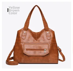 Front detail of a yellow brown PU leather tote bag with functional zipper pocket and straps