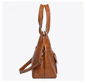 Side view of large brown PU leather tote bag with accordion fold and metal hardware