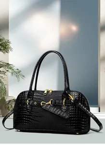 Detail of black crocodile pattern handbag with gold hardware and top handle design