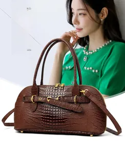 Detail of dark brown crocodile texture handbag with gold hardware and dual handles