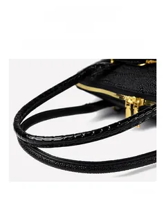 Close-up of black crocodile pattern leather with shiny texture and golden metal zipper detail