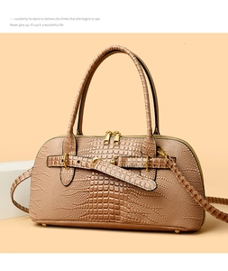Detail of warm apricot crocodile embossed texture handbag with gold hardware and strap