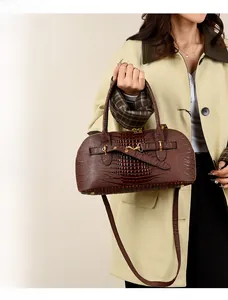 Detail of dark brown crocodile pattern handbag with gold metal clasp on a beige trench coat
