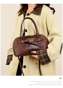 Close-up of deep brown crocodile embossed texture with golden metal hardware details