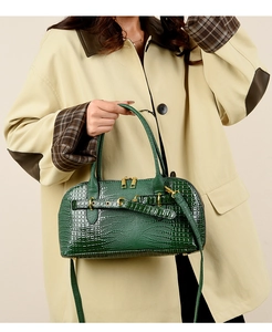 Detail of dark green crocodile pattern handbag with gold hardware and smooth zippers