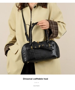Detail of black crocodile texture Boston bag with gold hardware on a beige trench coat