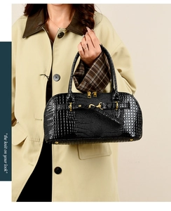 Classic black crocodile pattern handbag with gold hardware shown on a trench coat