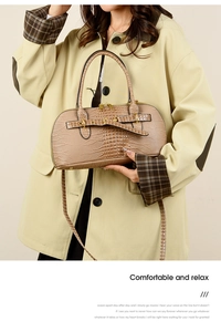 Detail of khaki crocodile pattern handbag with golden hardware on elegant beige coat