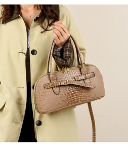 Detail of vintage brown crocodile texture handbag with gold buckle on a stylish model