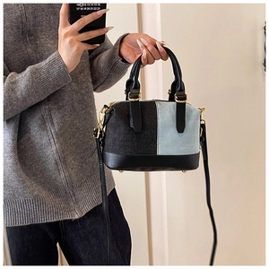 Detail view of denim patchwork Boston bag with leather handles and gold-tone hardware