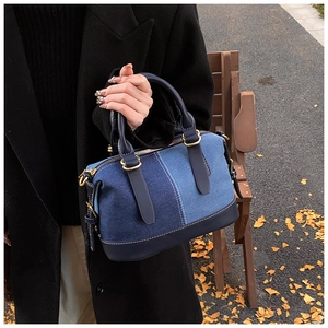 Detail of color-block denim Boston bag with leather handles and gold-tone hardware accents