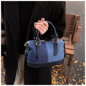 Detail of denim patchwork Boston bag with gold hardware and leather trim contrast