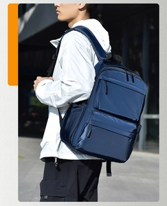 Outdoor shot of a man wearing a waterproof navy blue backpack with multiple zipper pockets