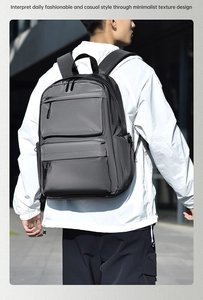 Detailed view of gray water-resistant nylon backpack showing front pockets and zipper texture