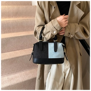 Detailed side view of a denim and leather patchwork handbag with gold metal hardware